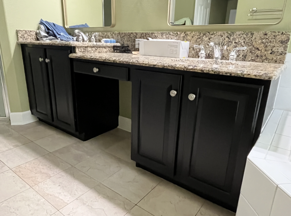 Black bathroom vanity with granite countertop and two sinks.