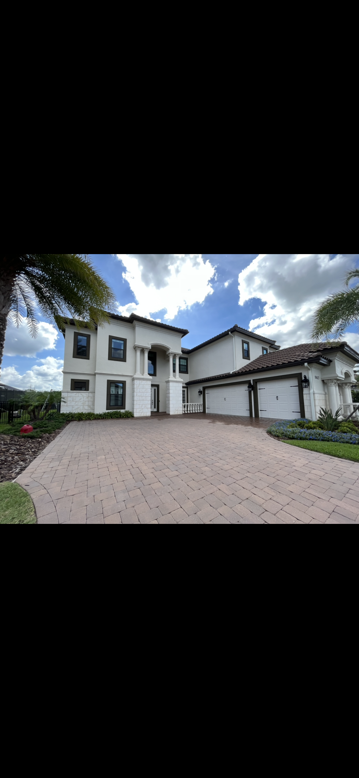 White stucco house with garage, driveway, and blue cloudy sky.