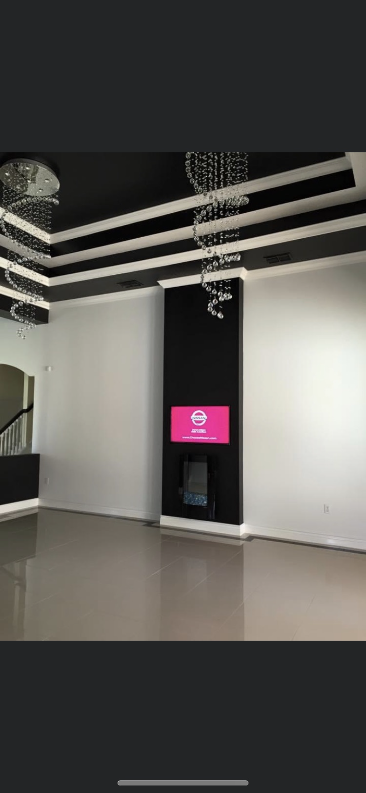 Empty modern room with black ceiling, white walls, and a pink digital display.