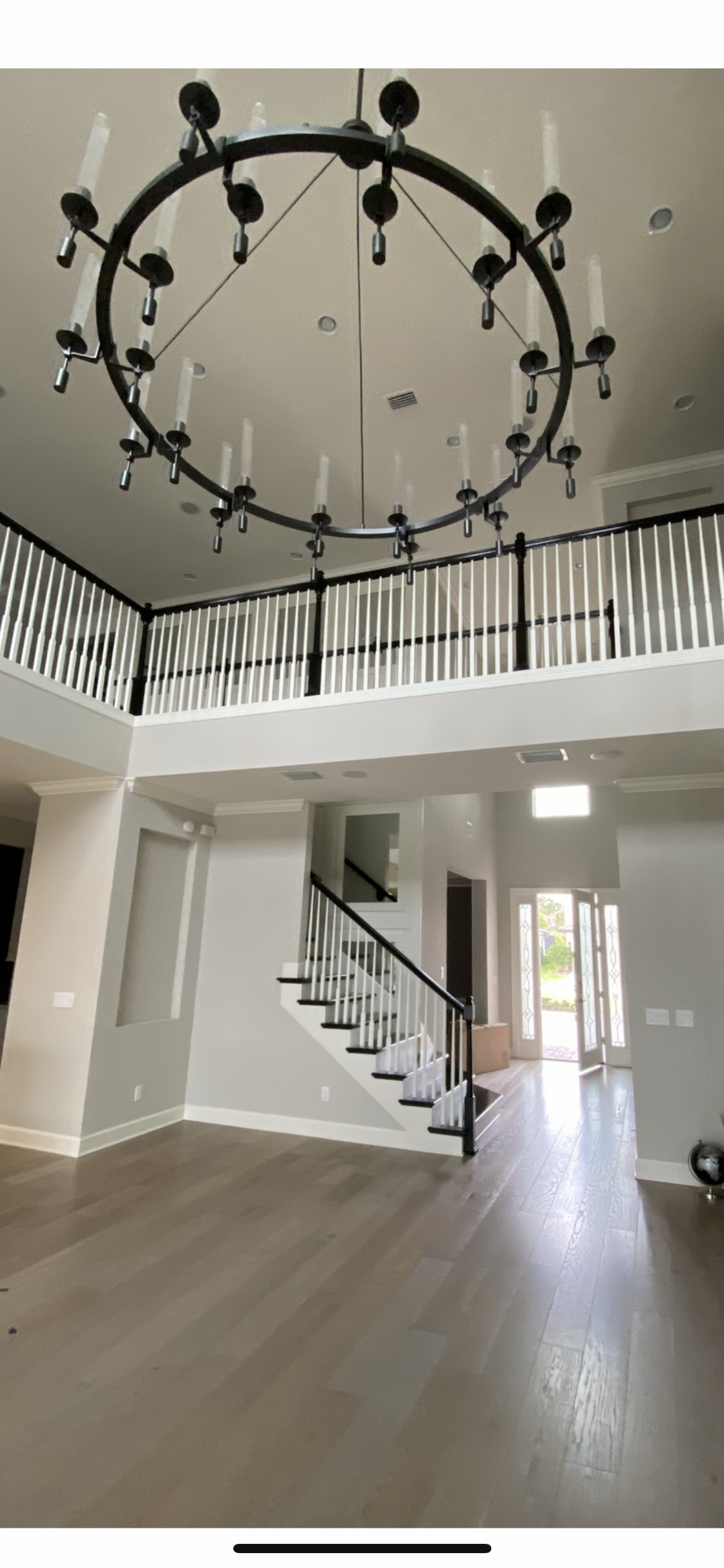 A large two-story foyer with a chandelier, staircase, and balcony.