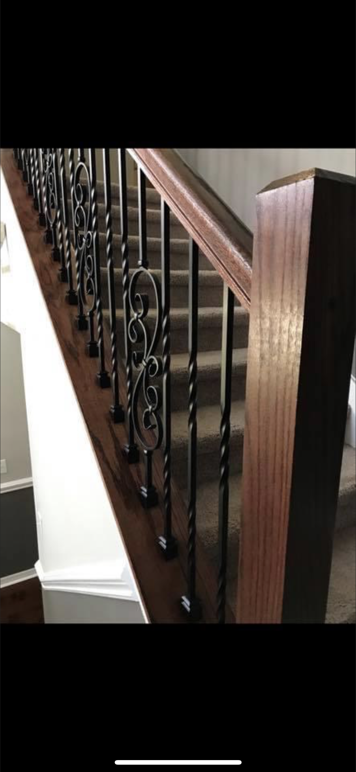 Wooden staircase with black wrought iron balusters.