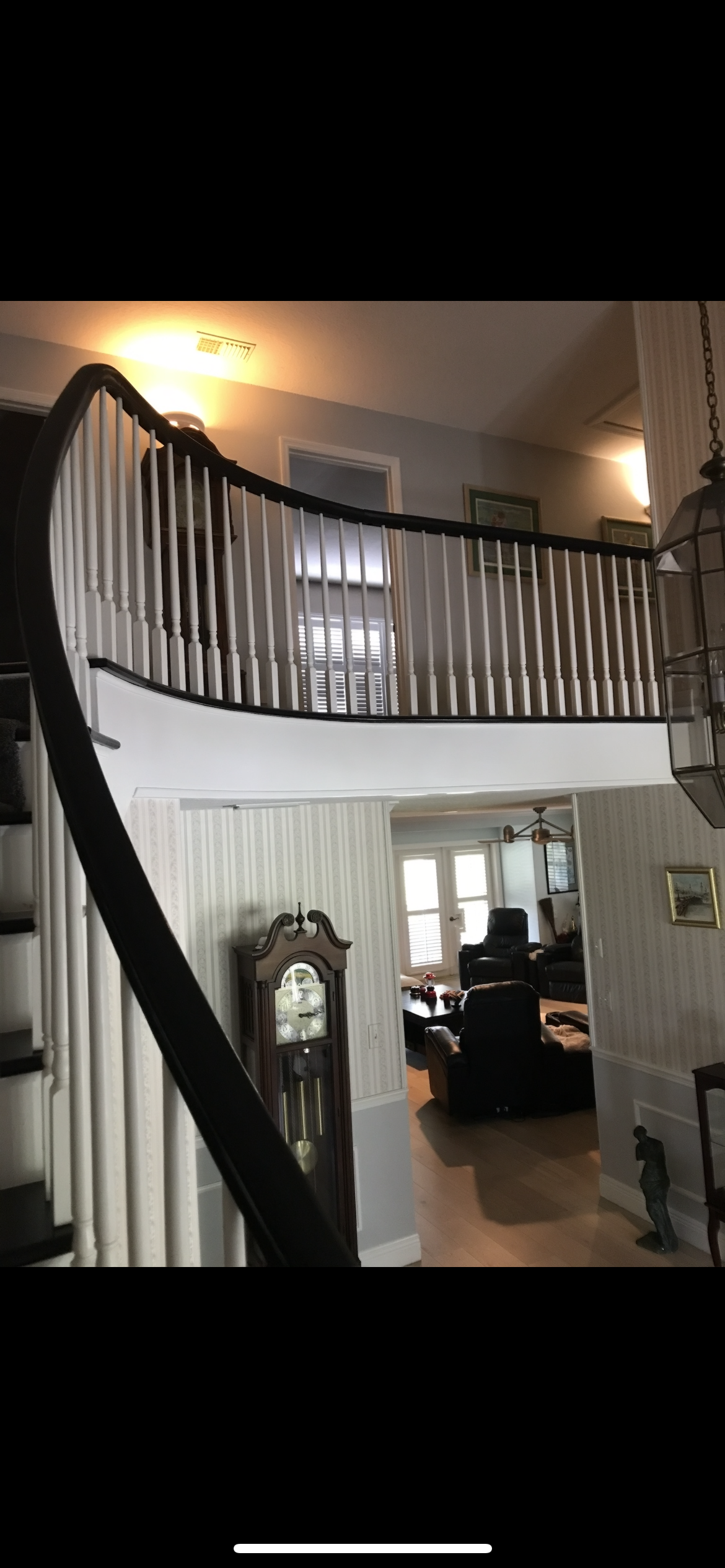Grand staircase with a curved banister and a grandfather clock in the entry hall.