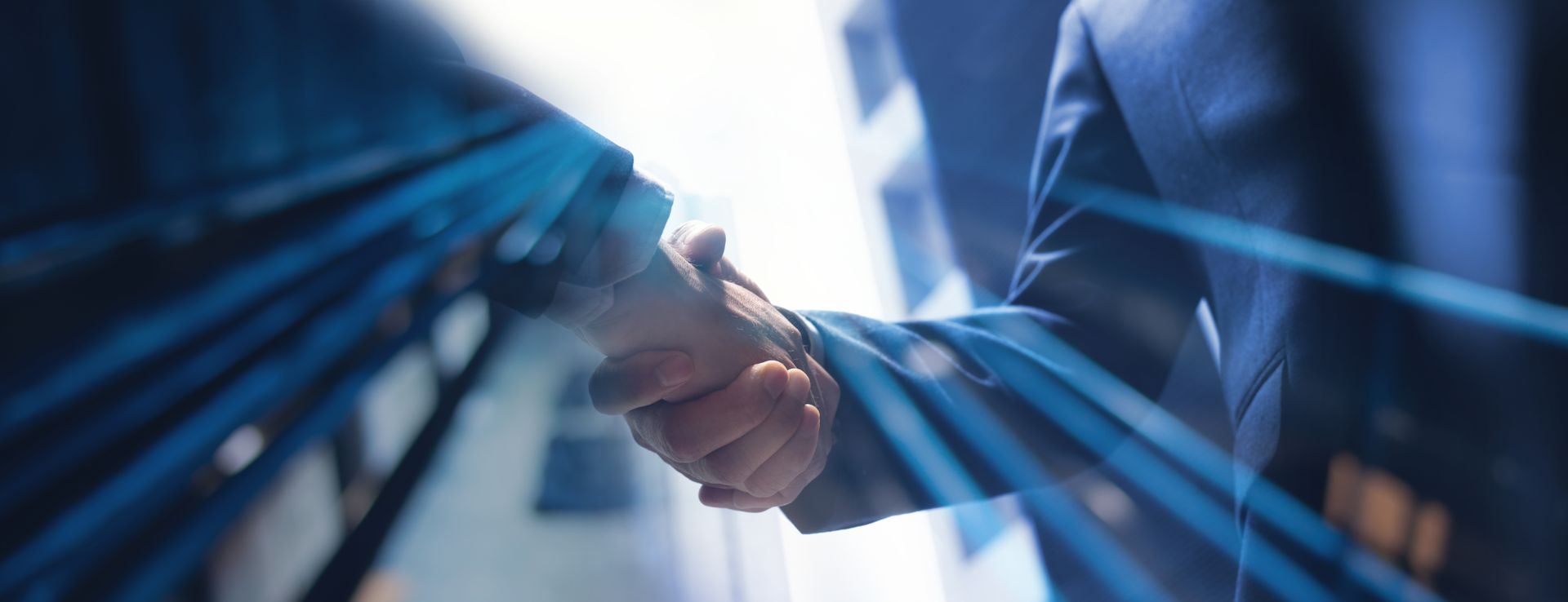 Two people in suits shaking hands, blue light beams overlayed.