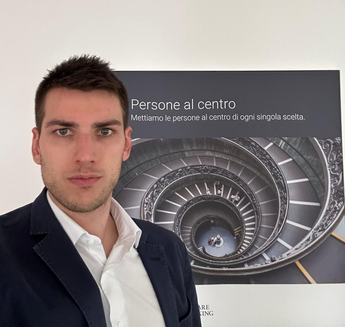 Un uomo in giacca e cravatta è in piedi davanti a un manifesto che dice persone al centro
