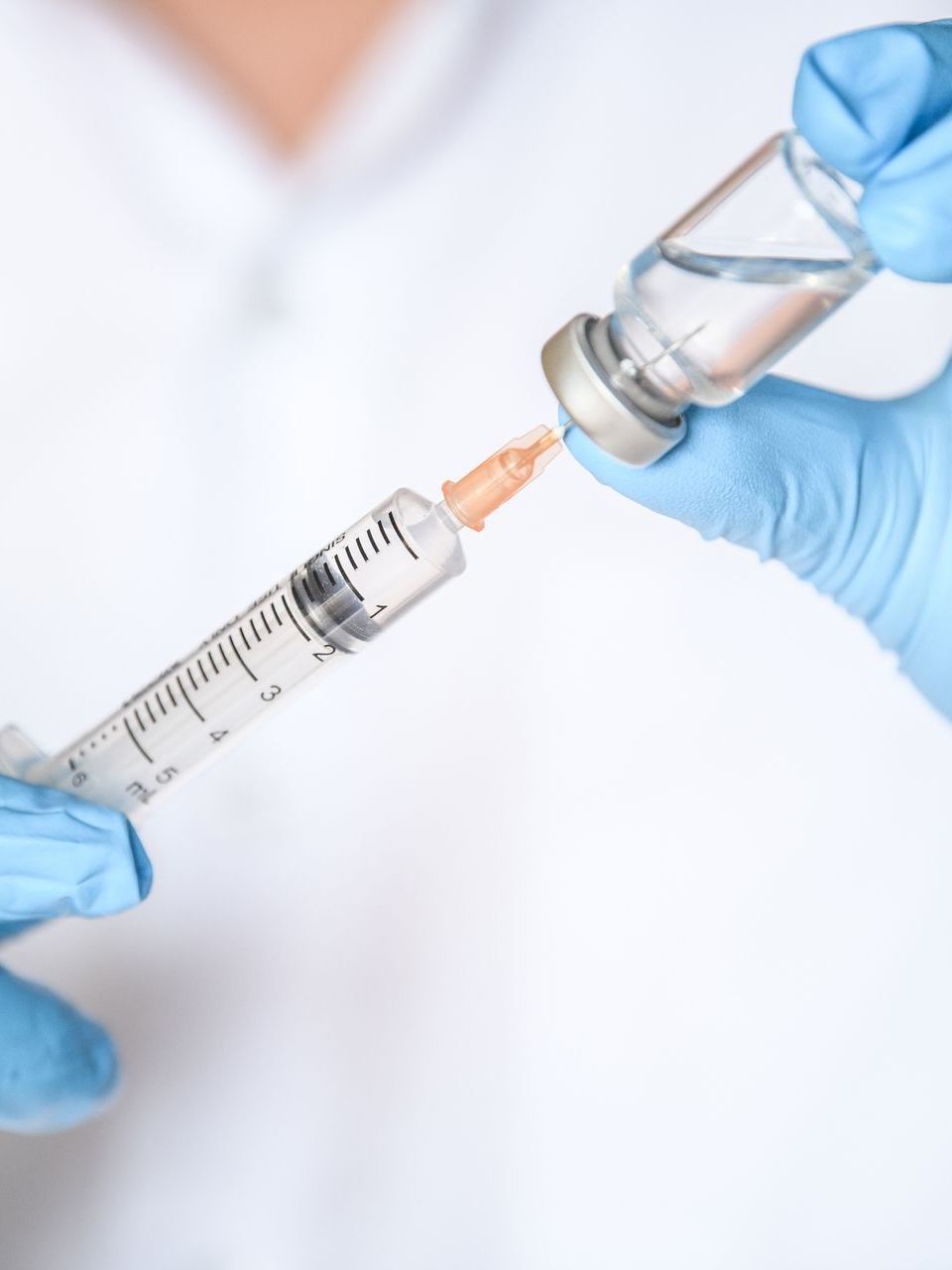 A doctor is holding a syringe and a bottle of vaccine.