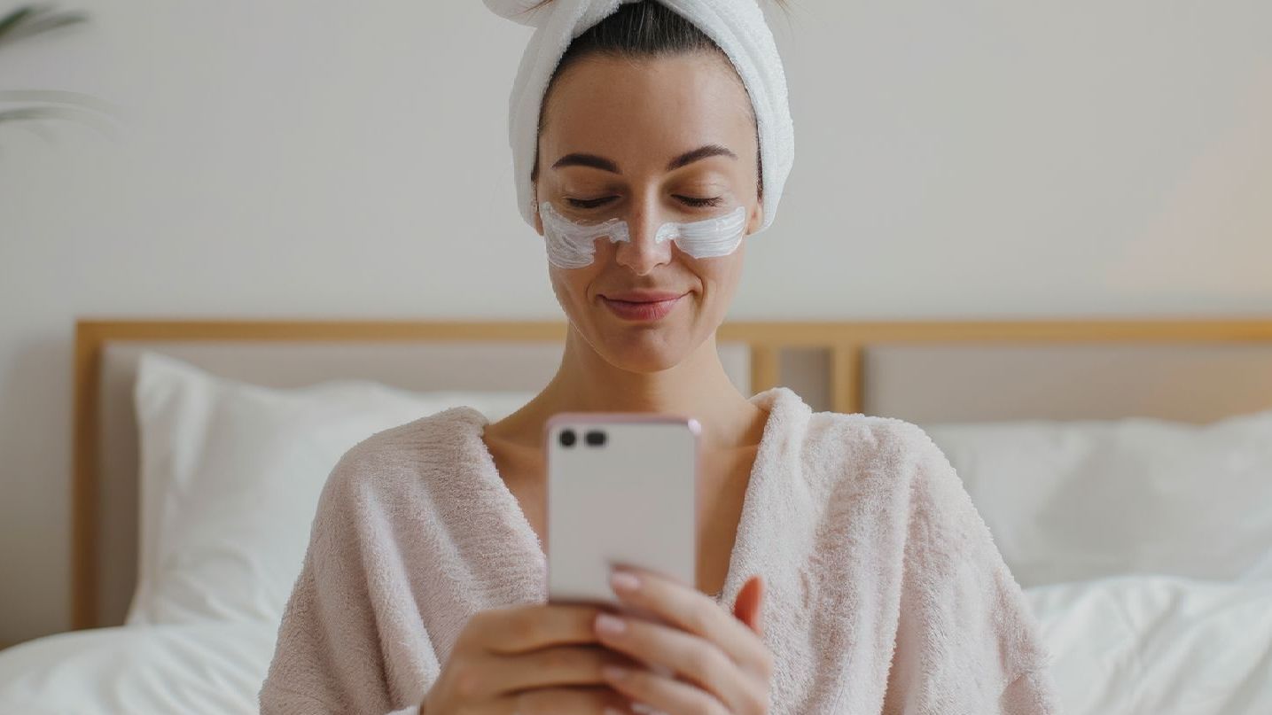 A woman with a towel wrapped around her head is using a cell phone.