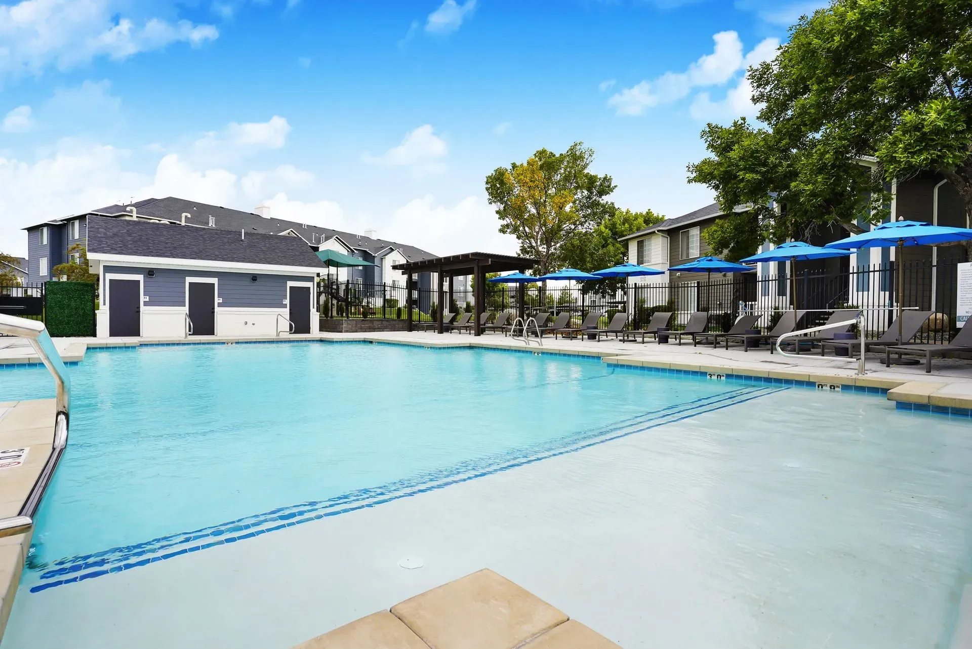 Outdoor swimming pool with lounge chairs and umbrellas.