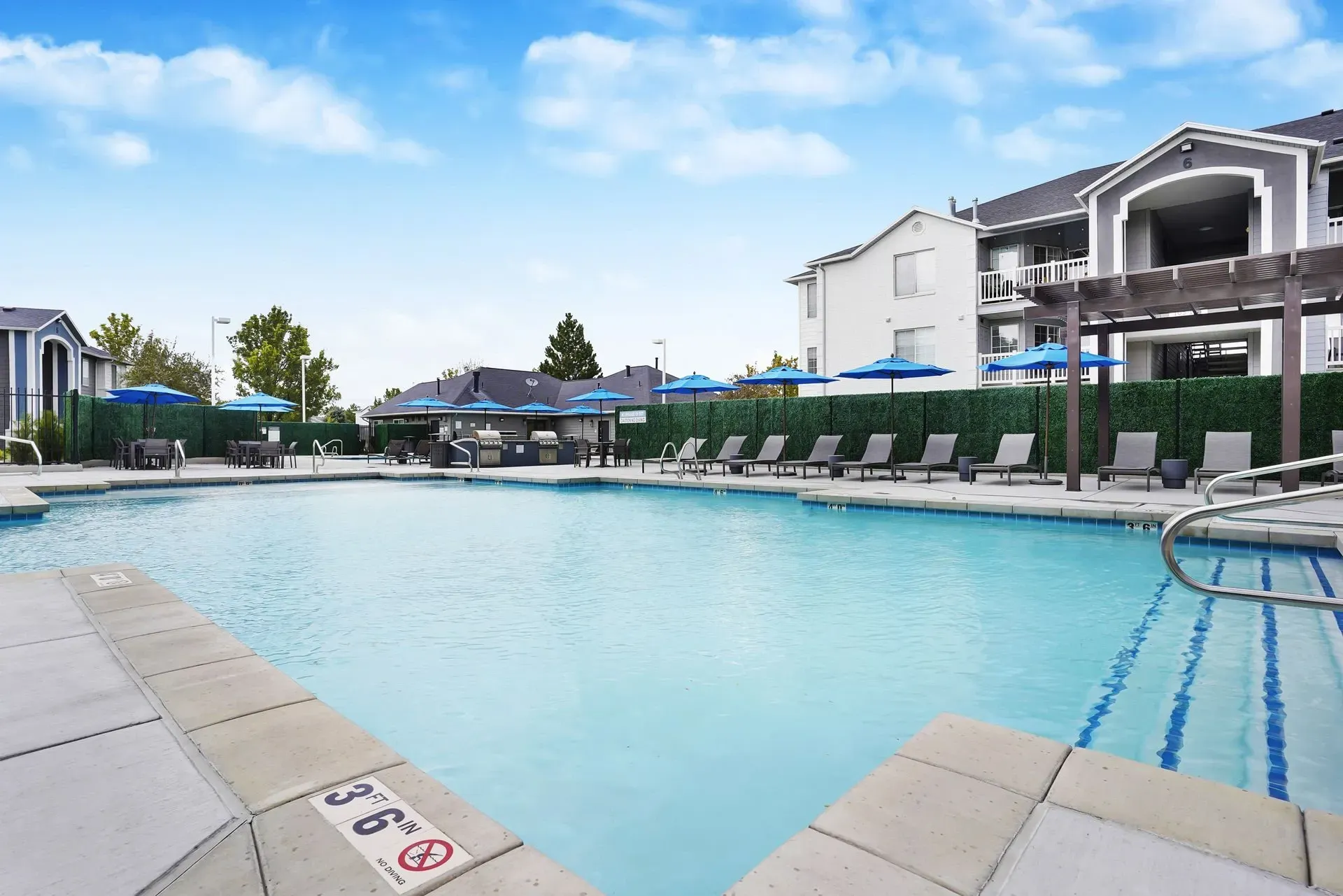 Outdoor swimming pool with lounge chairs and umbrellas.