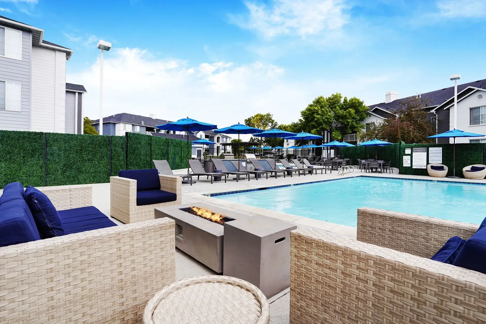 Outdoor swimming pool with lounge chairs, umbrellas, and seating areas.