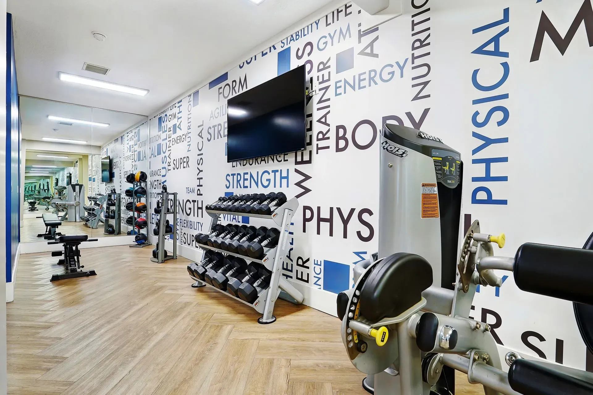 Gym with dumbbells, weight machines, and motivational wall art.