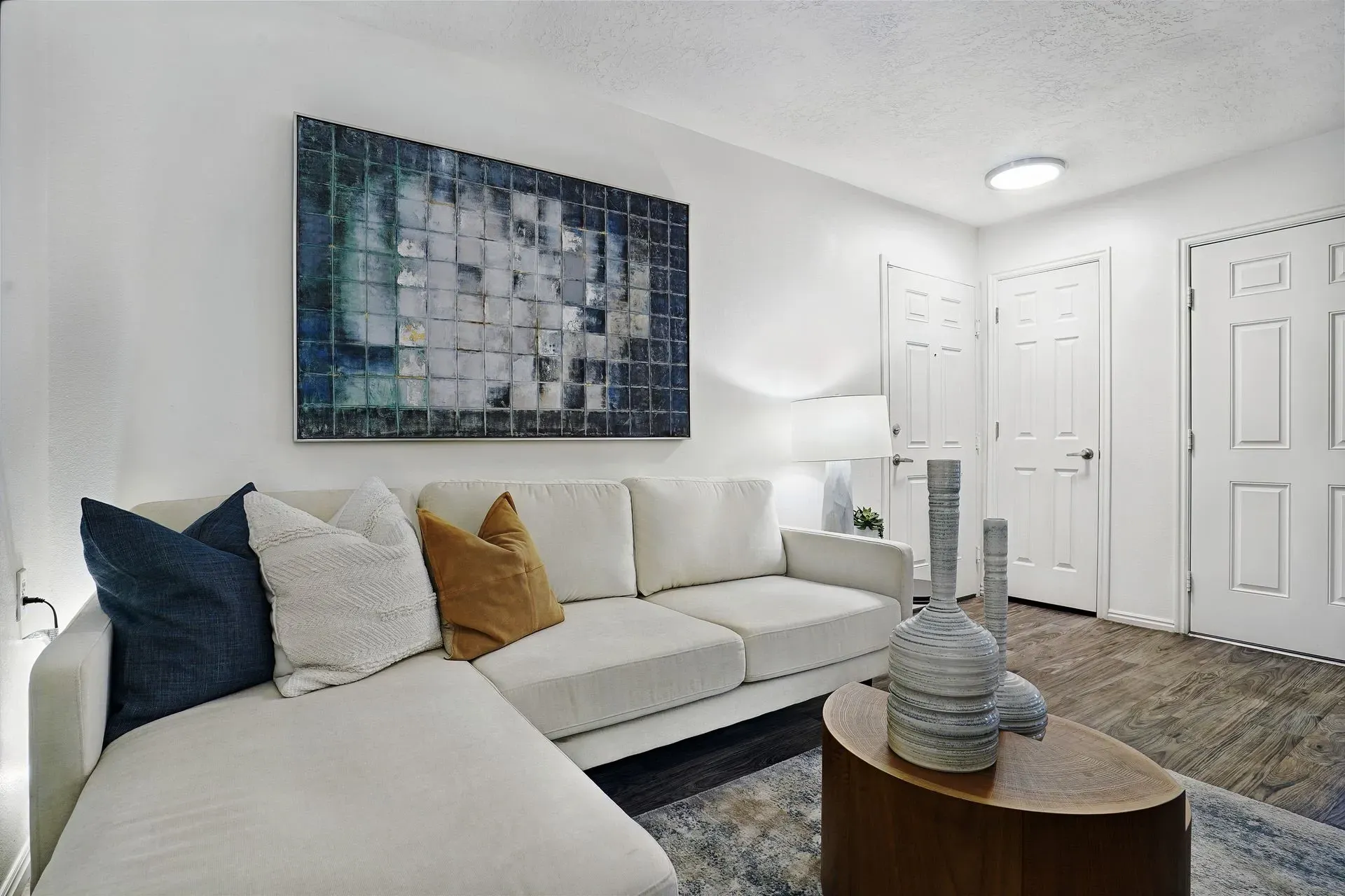 Stylish living room with a large sectional sofa, abstract art, and decorative vases.