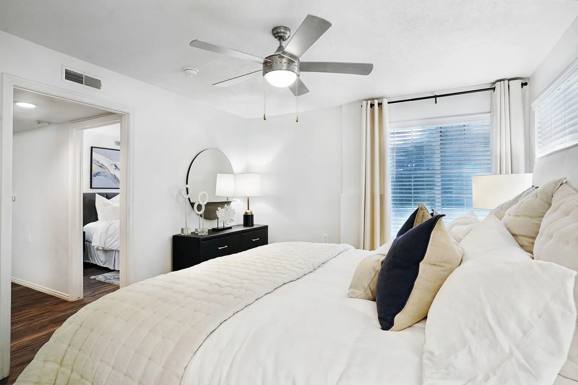 Bedroom with a large bed, ceiling fan, and dresser with a mirror.