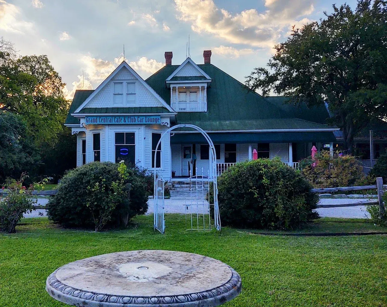 White Victorian-style house with green roof, porch, and lawn in evening light