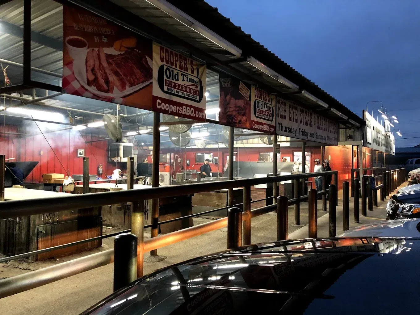 Outdoor food stall with bright red lighting and menu signs at night, seen along a snowy street