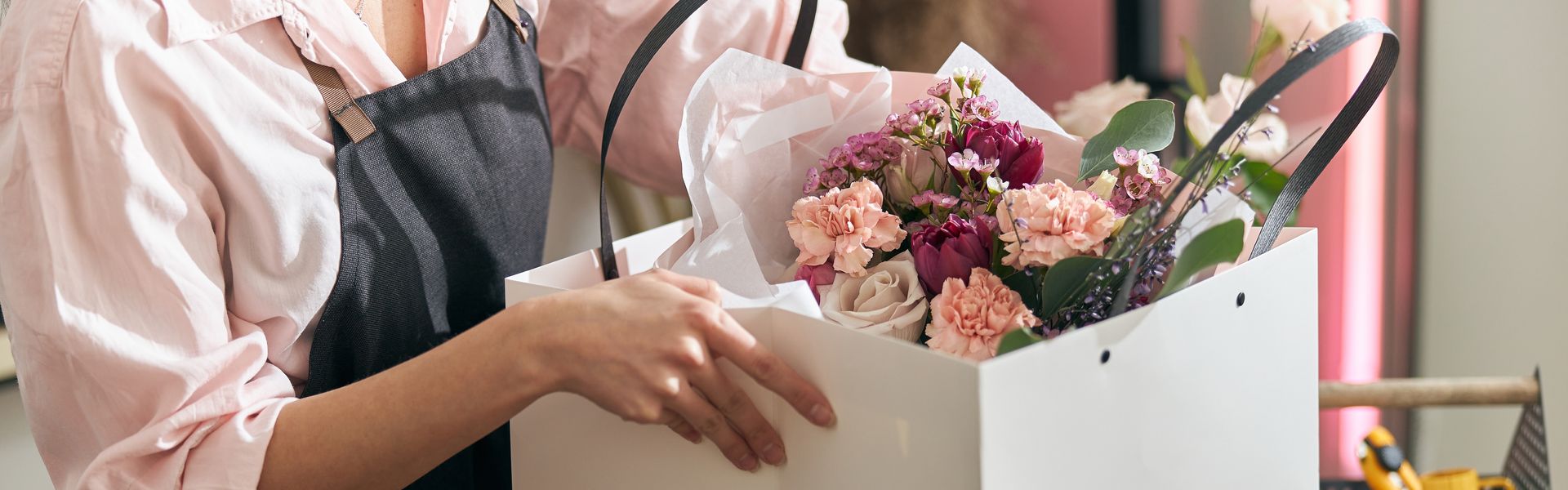 A basket filled with flowers is sitting on a wooden table.