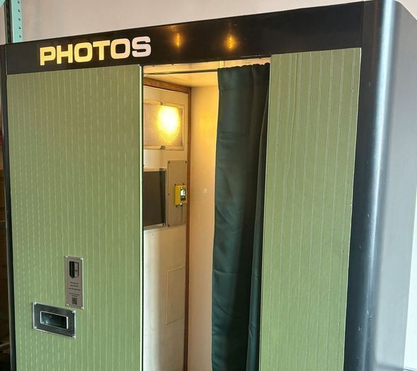 a photo booth with a black curtain and a sign that says photo booth .