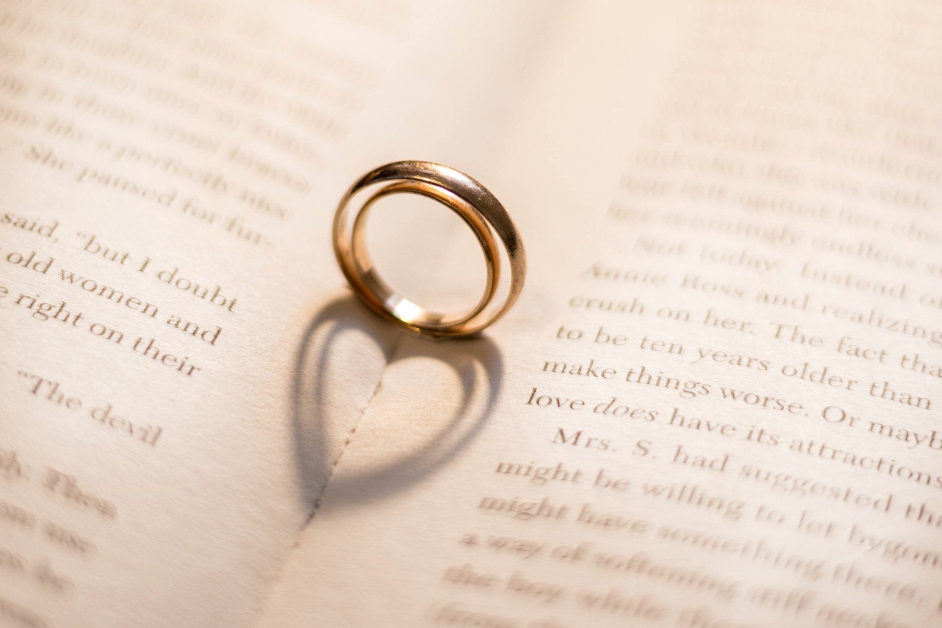 Two wedding rings on the book cast shadows in the form of hearts