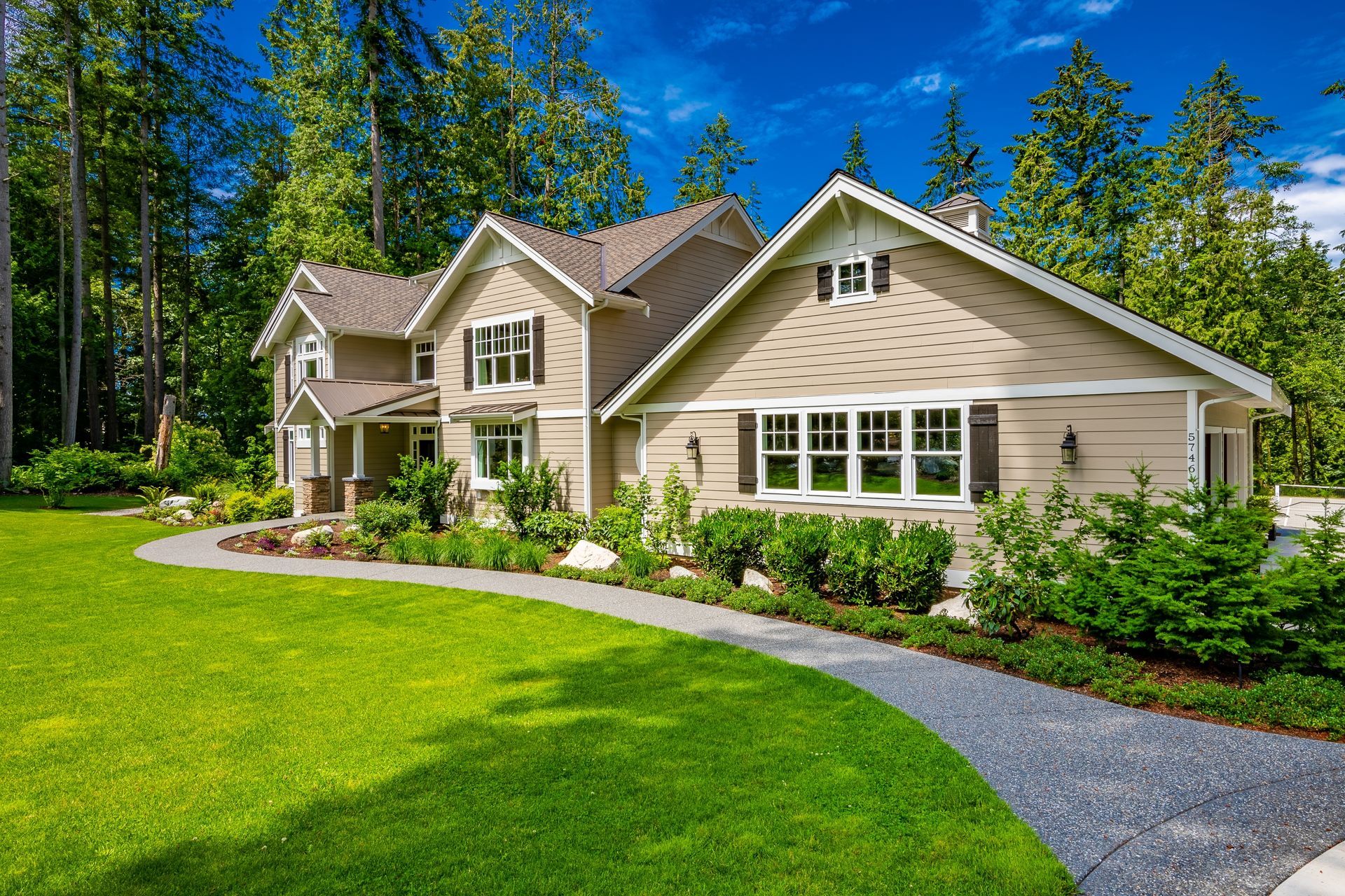 A large house with a lush green lawn and trees in the background.