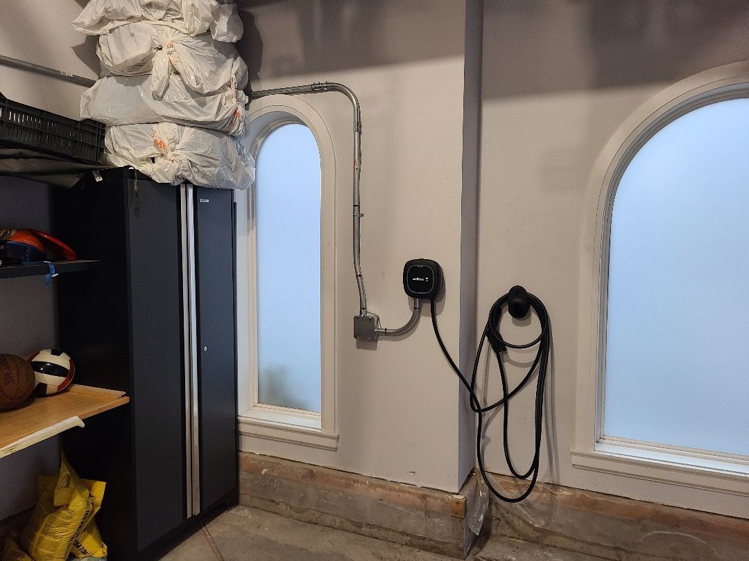 Garage interior with electrical outlets, arched windows, and a black cabinet.