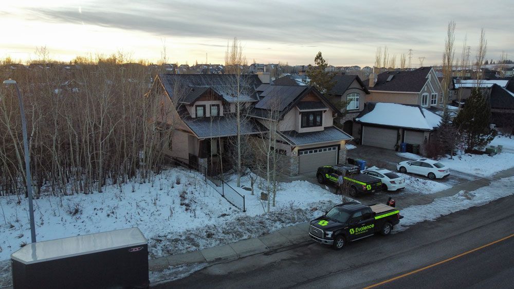House exterior with police vehicles parked in the driveway; snow-covered ground and trees.