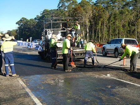 A Group of Construction Workers Are Working on A Road — Roll Formed Driveways in Yandina, QLD