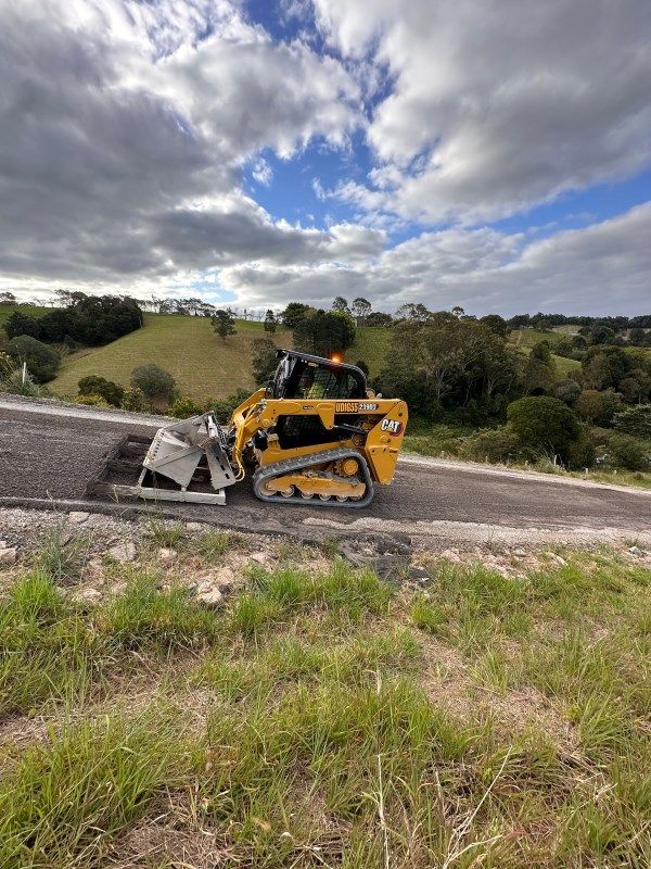 A Bulldozer Is Driving Down A Hill On A Cloudy Day — Roll Formed Driveways in Caboolture, QLD