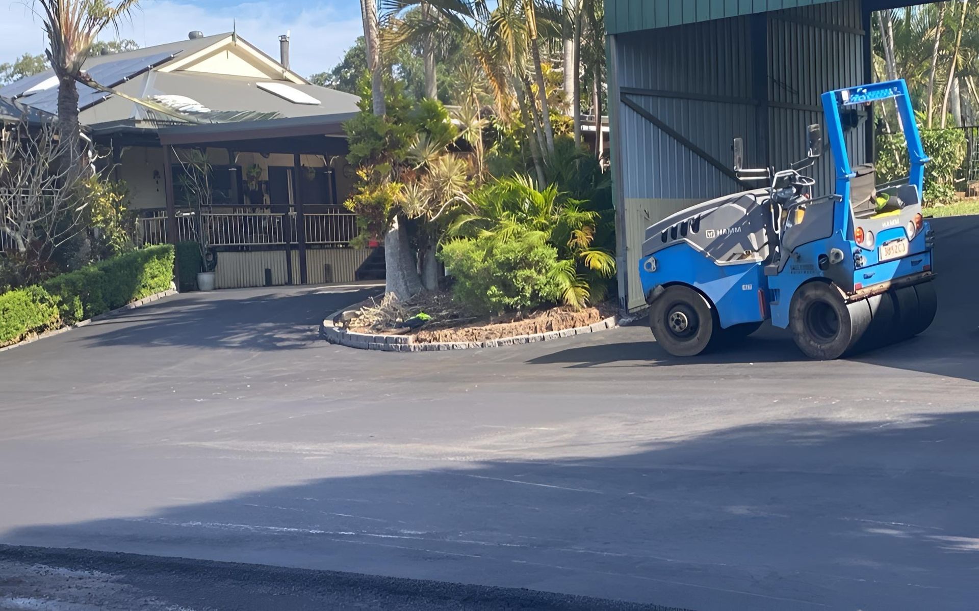 A Blue Roller Is Sitting In Front Of A House — Roll Formed Driveways in Gympie, QLD