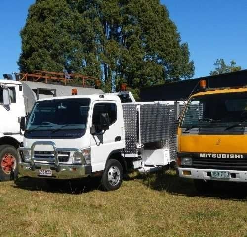 Two Trucks Are Parked in A Grassy Field — Roll Formed Driveways in Yandina, QLD