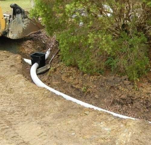 A Bulldozer Is Digging a Hole in The Ground with A Hose Attached to It — Roll Formed Driveways in Yandina, QLD