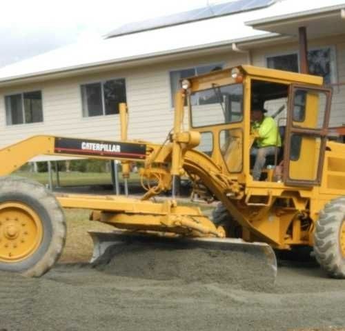 A Yellow Caterpillar Tractor Is Parked in Front of A House — Roll Formed Driveways in Yandina, QLD