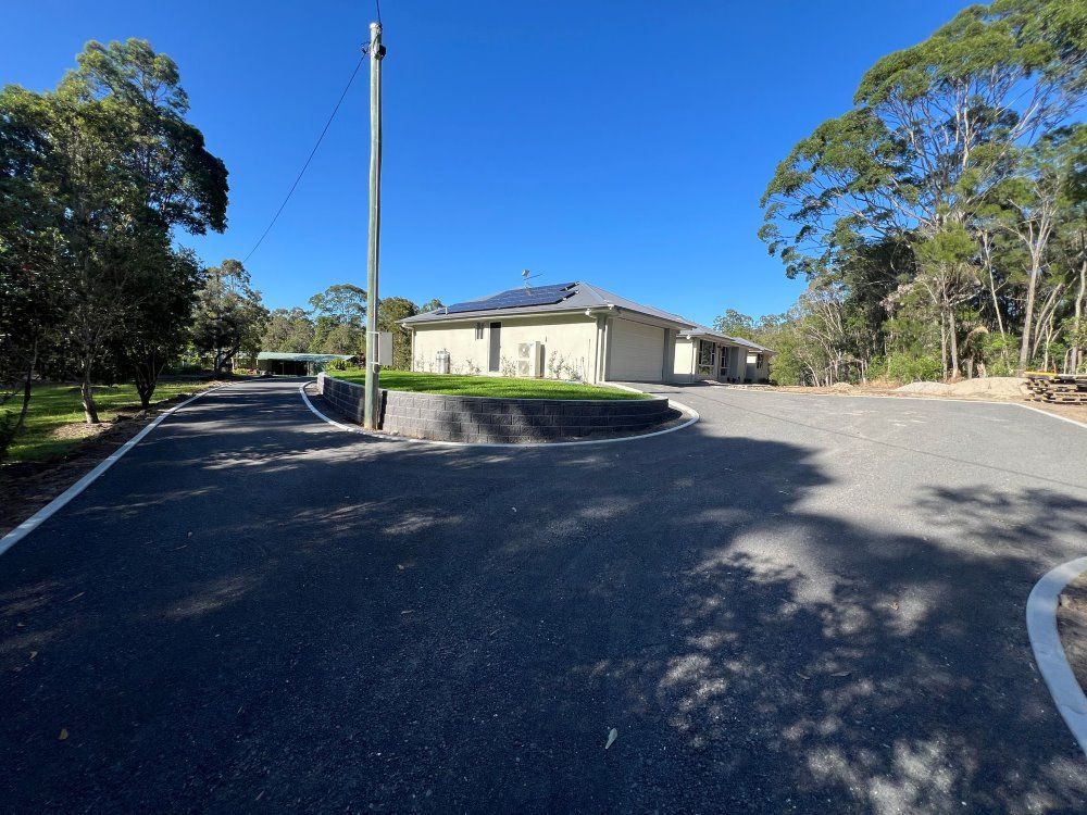 A House Sits On The Side Of A Road Surrounded By Trees — Roll Formed Driveways in Nambour, QLD