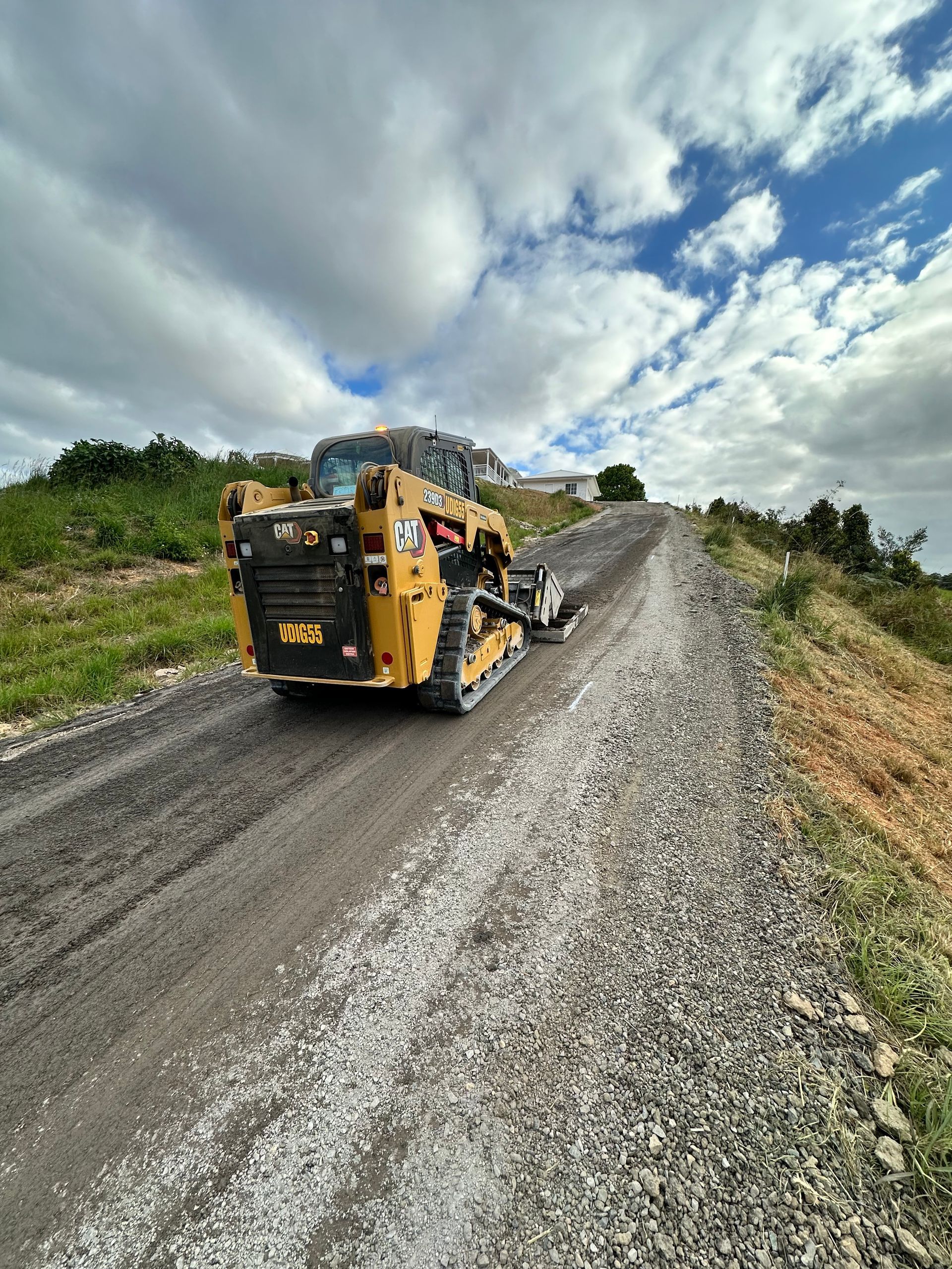A bulldozer is driving down a gravel road — Roll Formed Driveways in Yandina, QLD