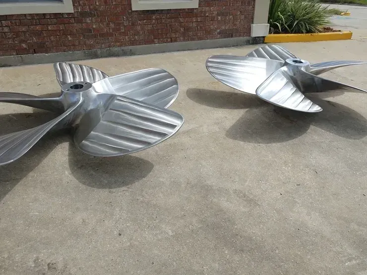 Two metal propellers are sitting on the ground in front of a brick building