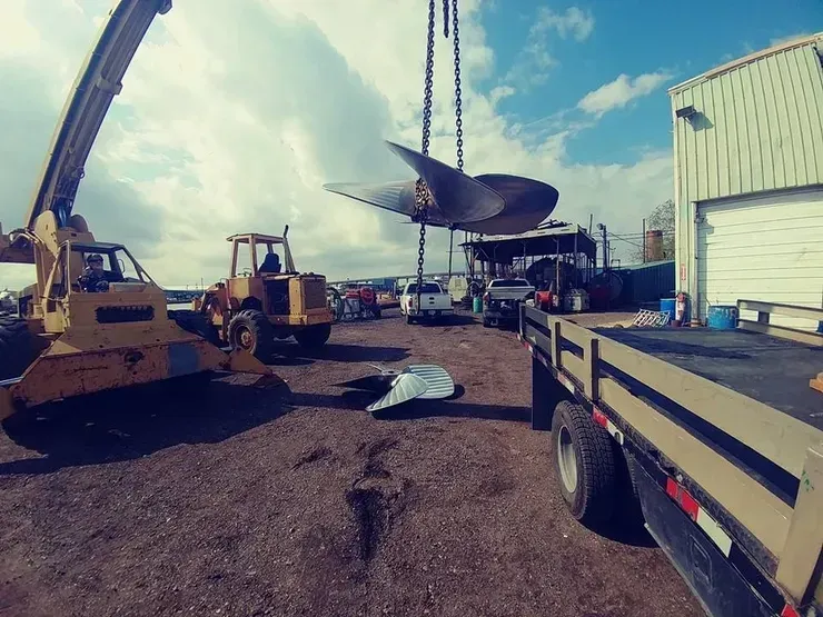 A large propeller is being lifted into the air by a crane.