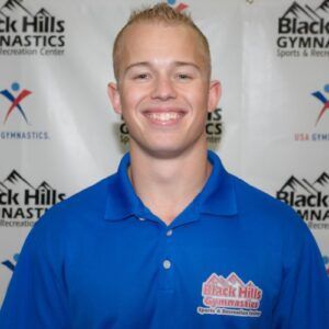 A man wearing a blue shirt that says black hills gymnastics