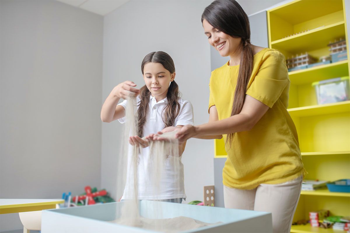 Woman and child mixing ingredients at a table in a bright classroom