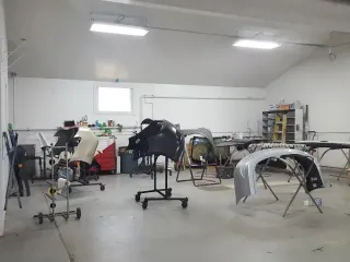 Auto body shop with several car parts and frames arranged in a workshop