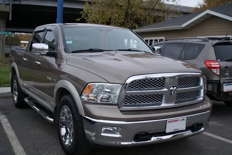 Beige Ram pickup truck parked in a lot, front three-quarter view.