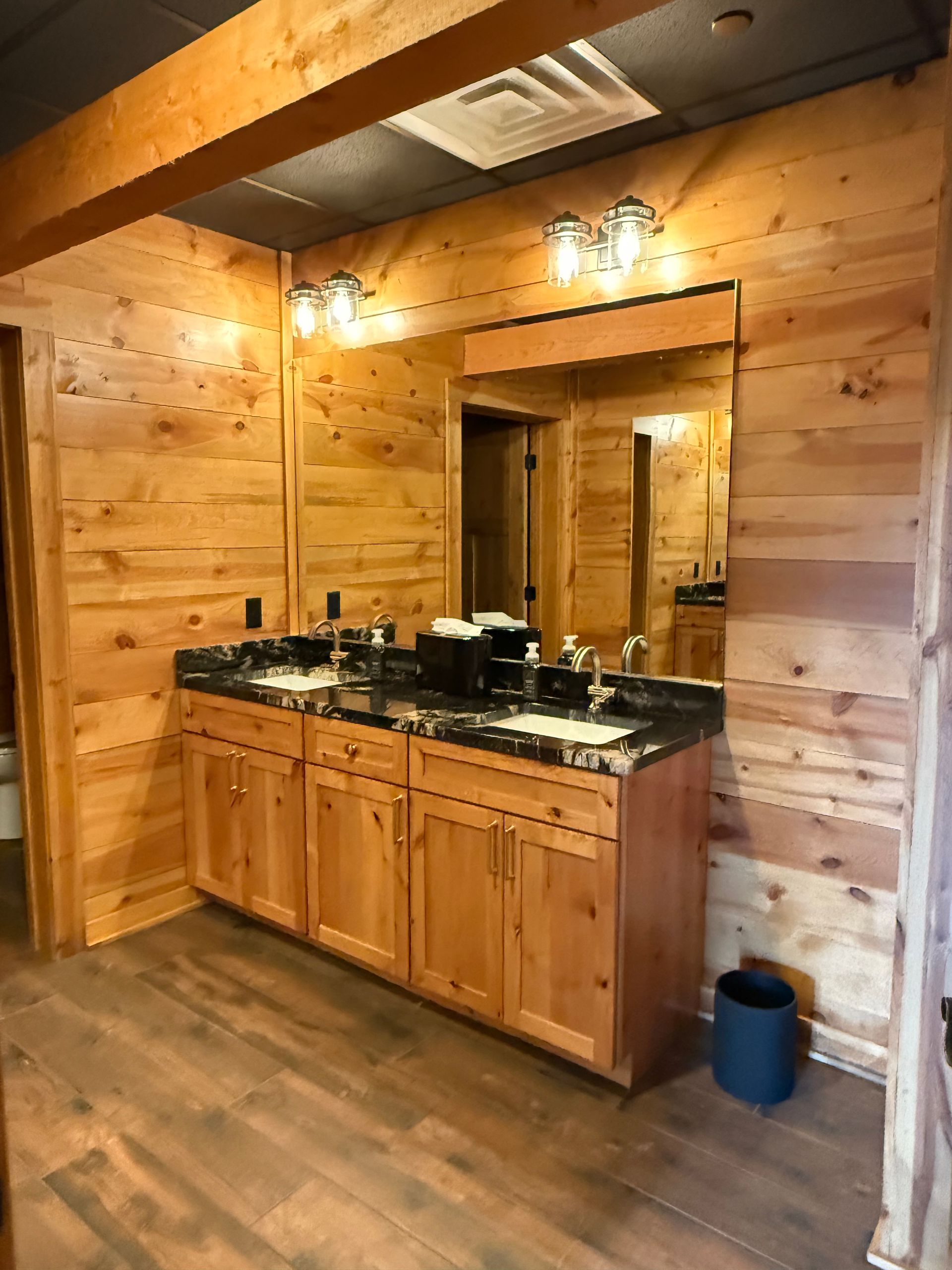 Wood-paneled rustic kitchen with a granite sink cabinet and warm overhead lights