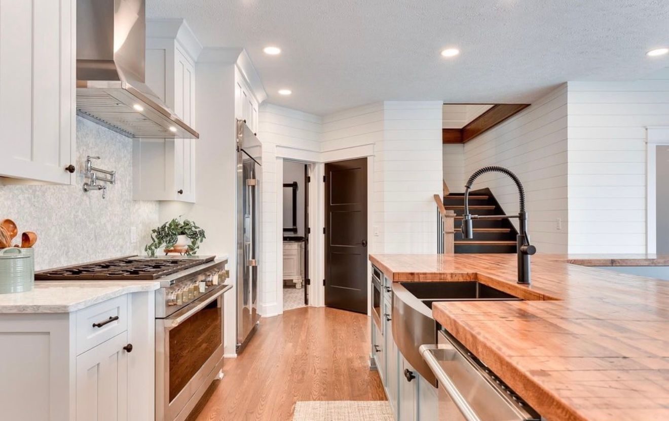 Bright modern kitchen with white cabinets, wood island, and stainless steel appliances