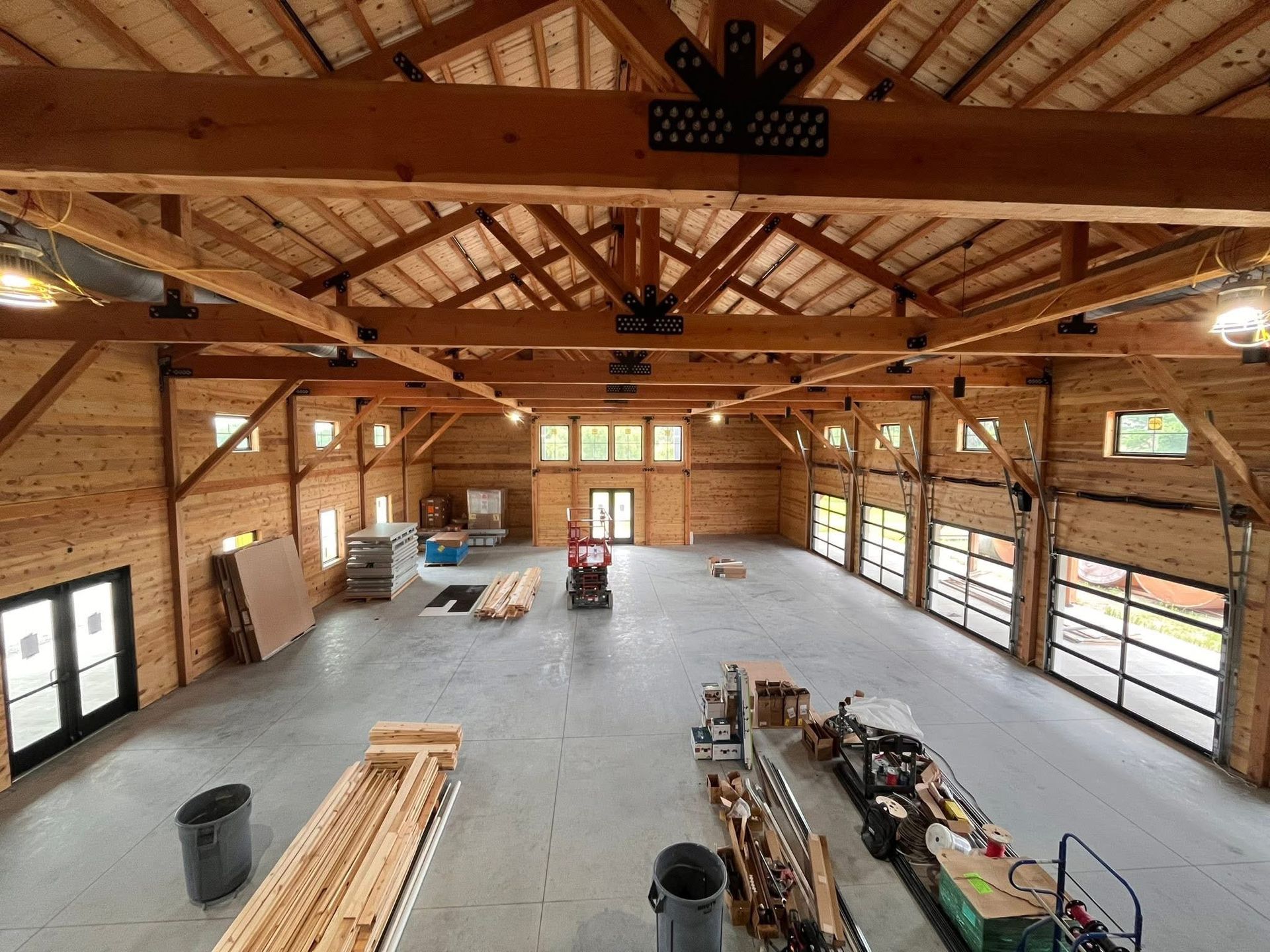 Spacious unfinished wooden workshop interior with exposed beams, tools, and construction materials.