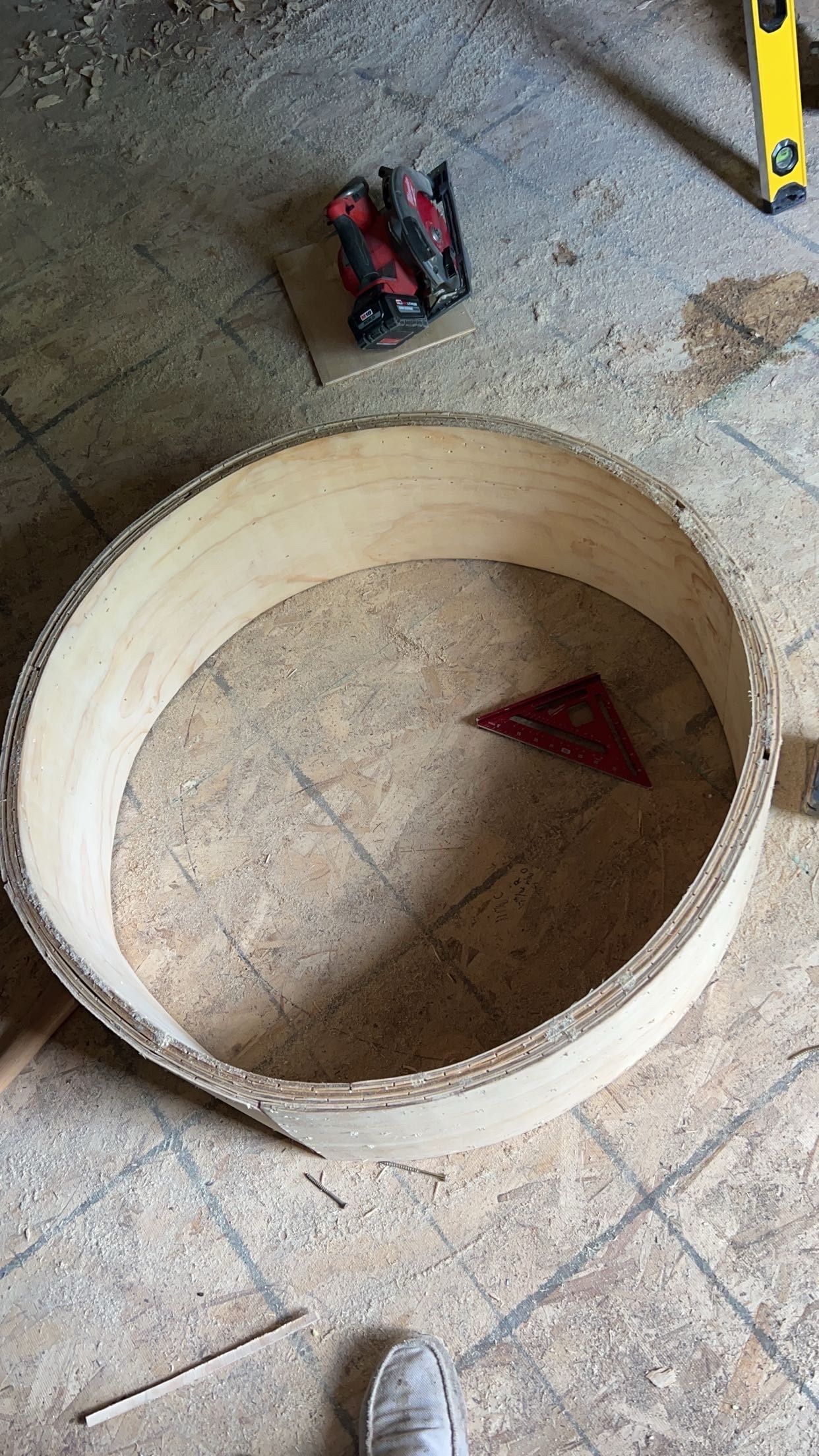 Large beige circular ring on a tiled floor, with a red triangular piece inside and tools nearby.