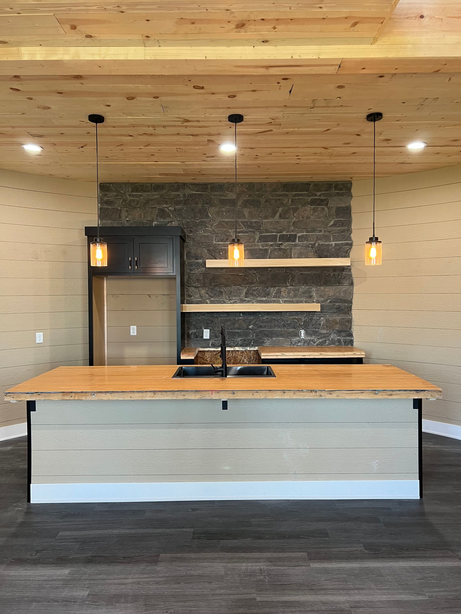 Modern kitchen with wood ceiling, gray stone backsplash, and large island countertop