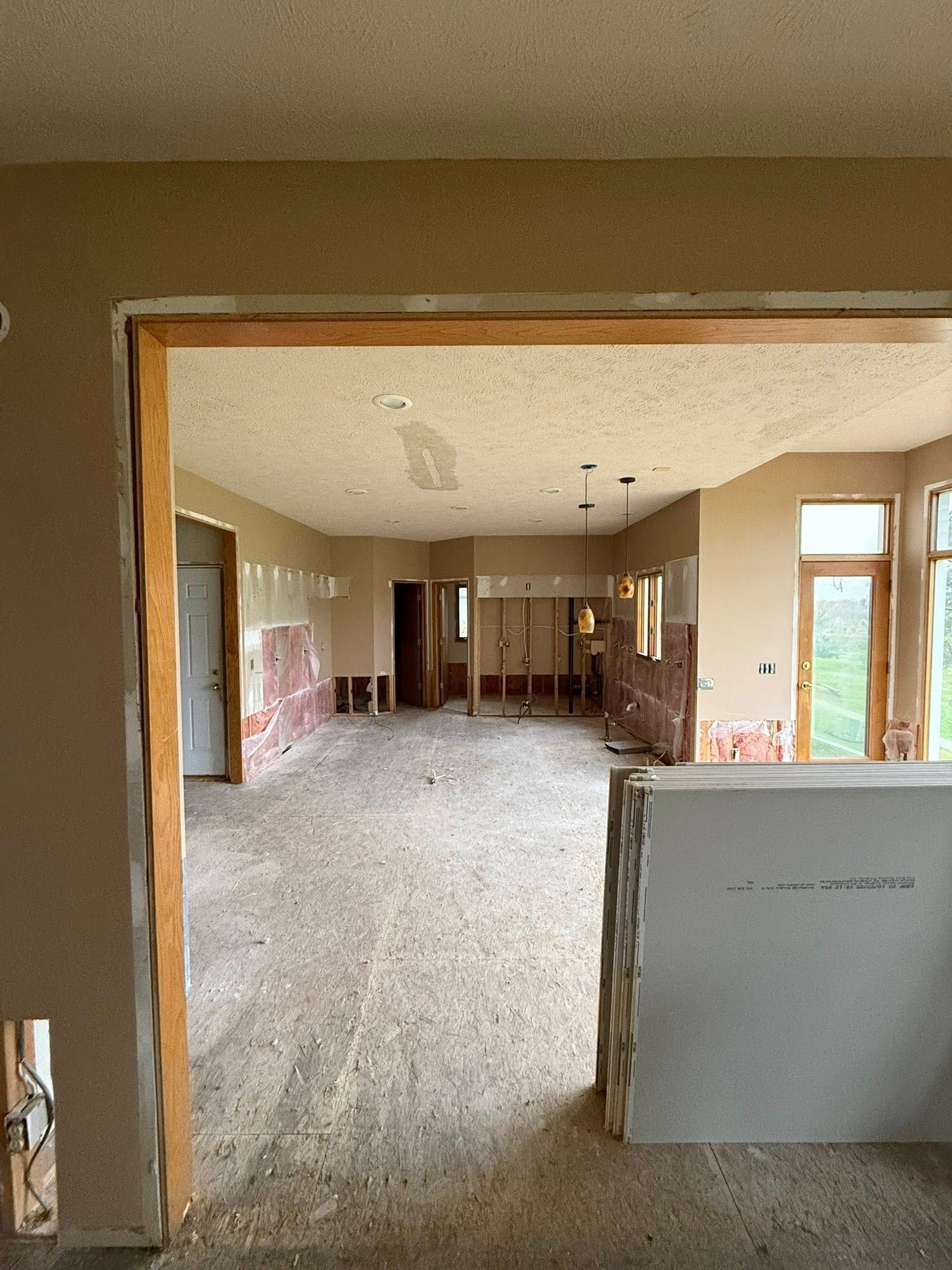 Interior of an unfinished room with exposed drywall, carpet, and large windows looking into another space