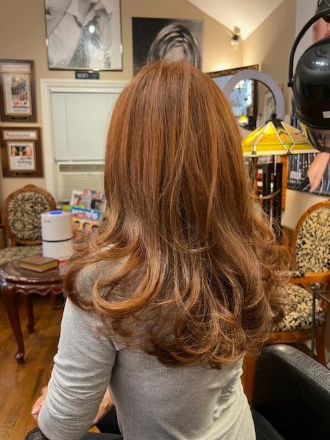 A woman with long red hair is sitting in a chair in a salon.