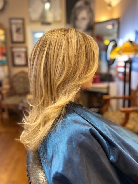 A woman with blonde hair is sitting in a chair in a salon.