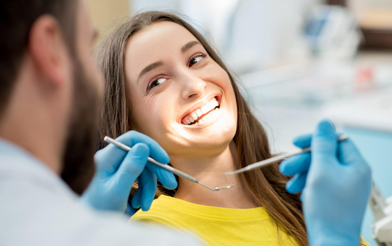 Woman at the dentist's office with mouth open as a dental professional examines teeth.