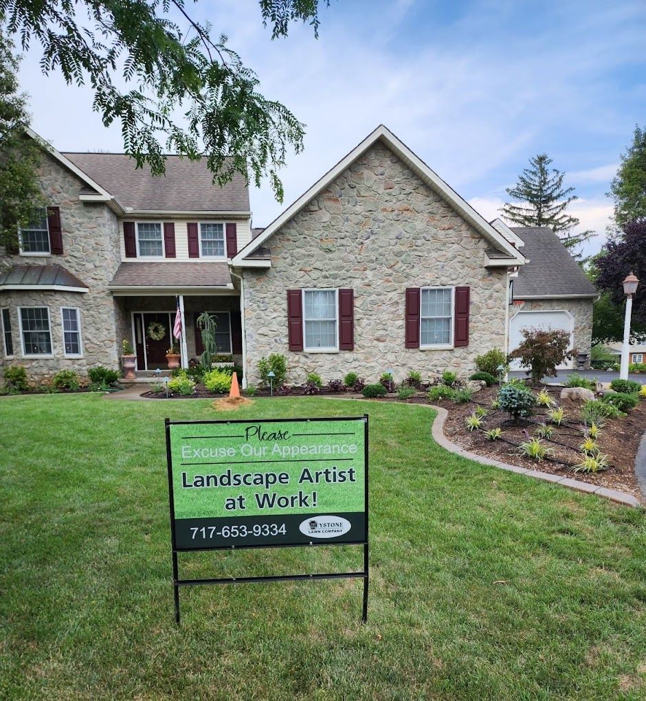 A house with a sign in front of it that says landscape artist at work