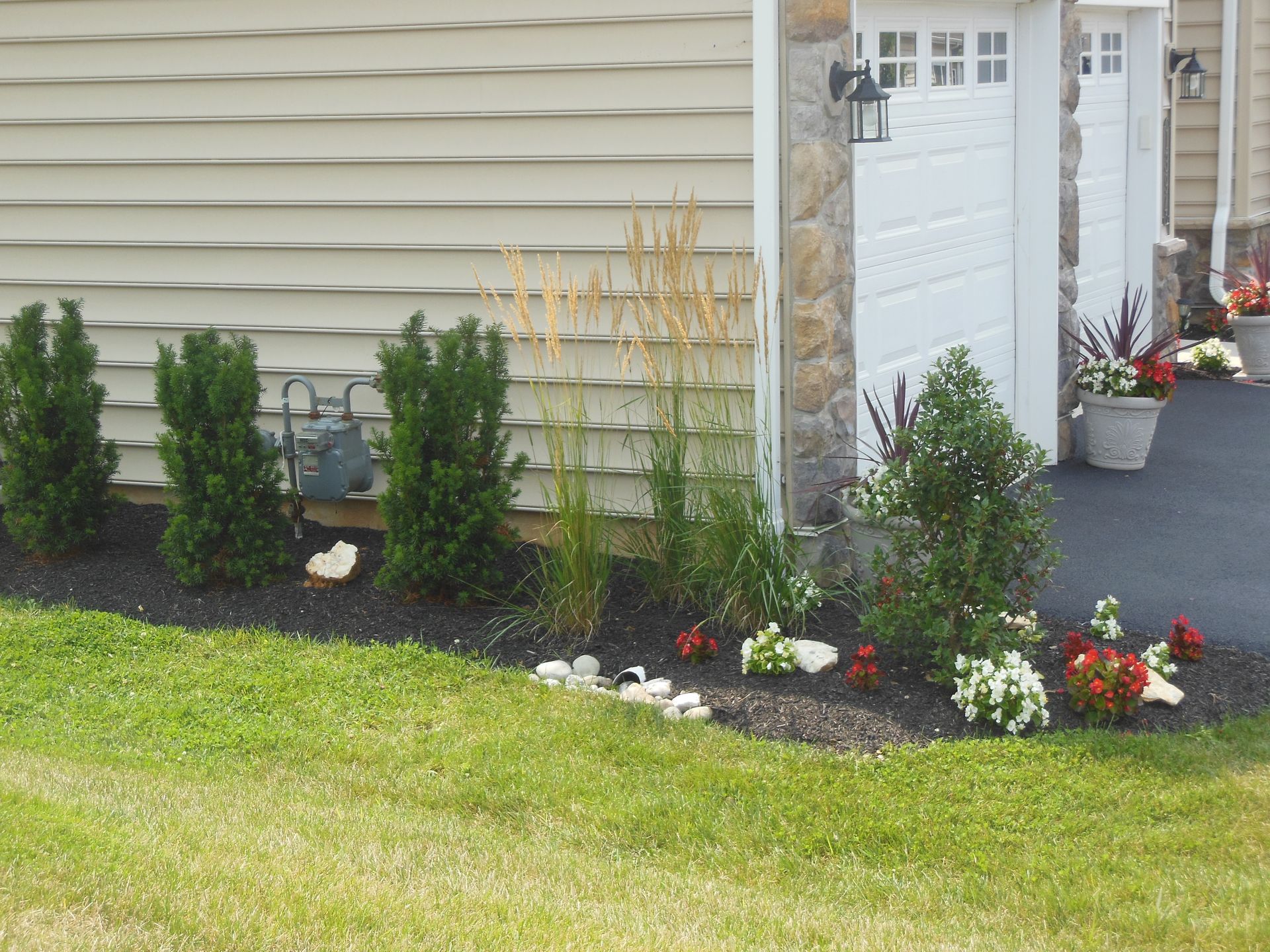 A lawn with flowers and bushes in front of a house