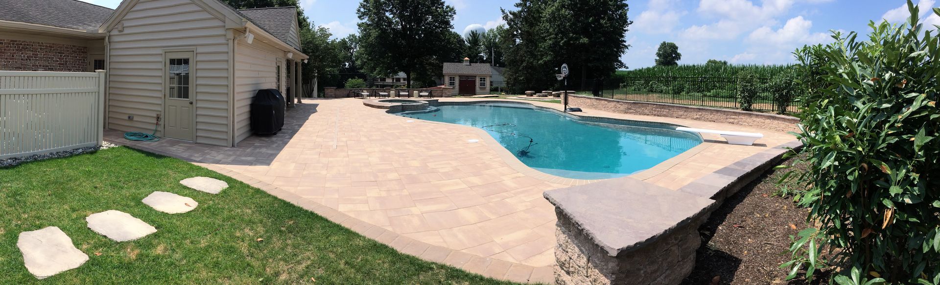 A large swimming pool is in the backyard of a house.